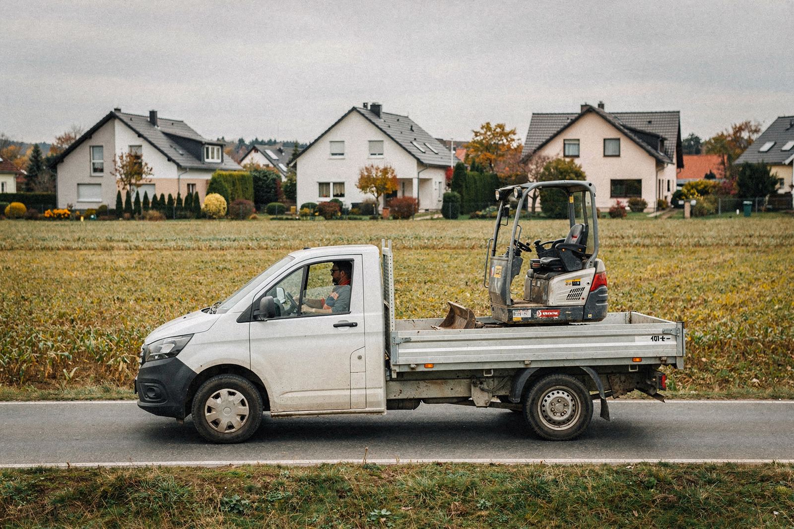 Symbolbild: Transporter mit Minibagger auf einer Landstraße