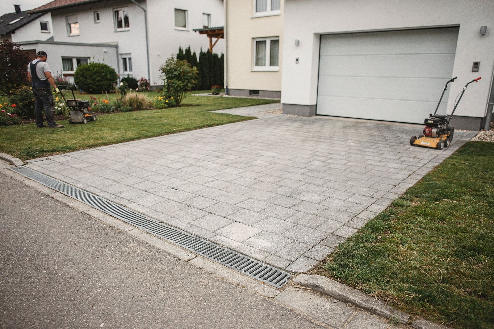 Symbolbild: Hofeinfahrt aus grauem Betonpflaster mit Randeinfassung vor einem Einfamilienhaus